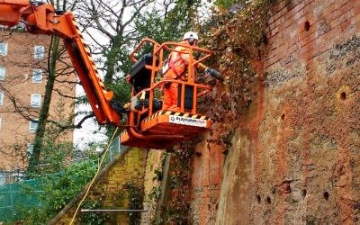 Rear 03 cherry picker being used to core holes in a retaining wall to drive earth anchors through