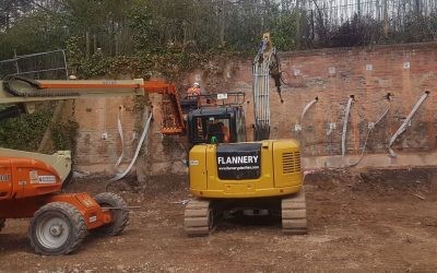 Rear 04 excavator and cherry picker being used to drive and load lock percussion driven earth anchors