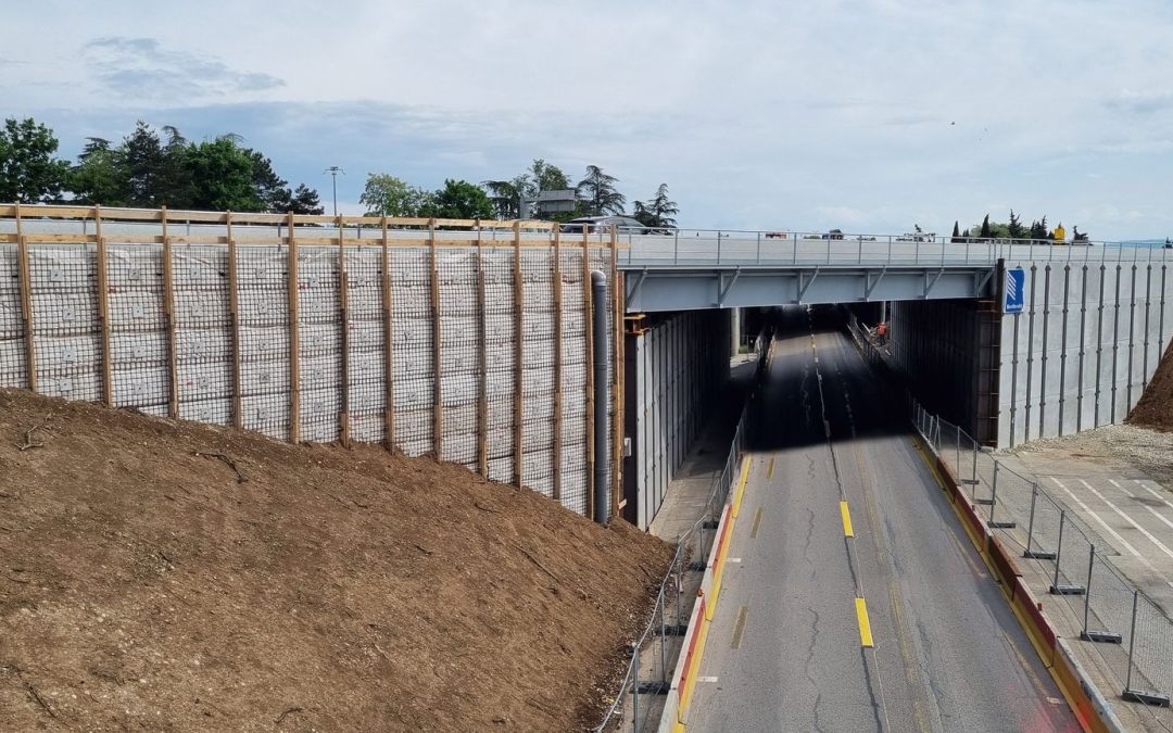 Timber soldiers and wire mesh supporting engineered soil along the side of a motor bridge