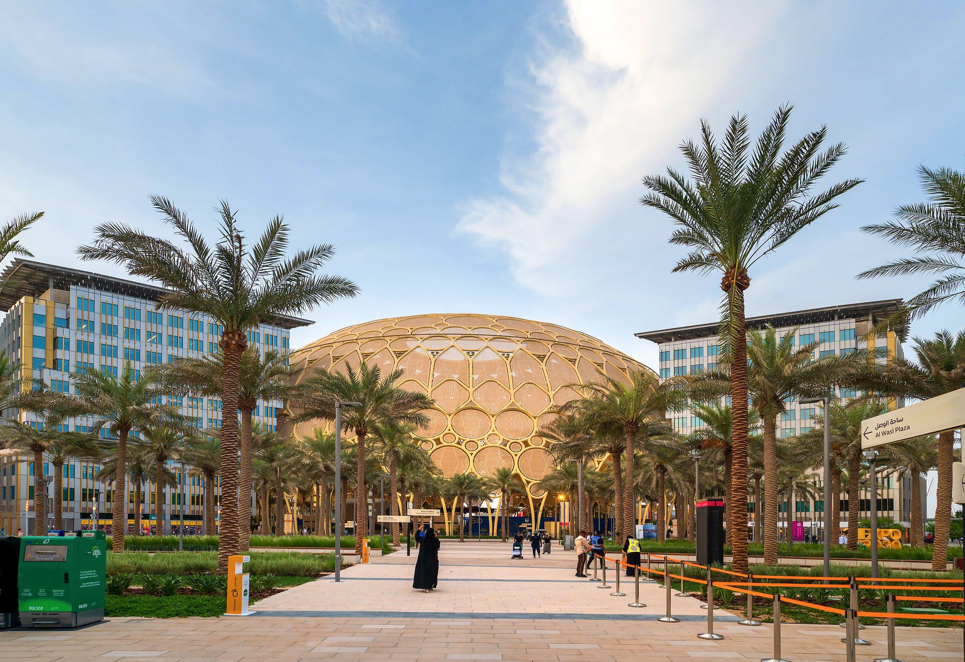 01 Al Wasl Plaza's golden dome surrounded by palm trees and modern buildings at a public square.